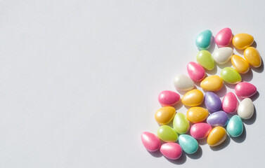 Colored candies in the form of eggs on a white background. Chocolate Easter candies covered with multicolored sugar glaze.