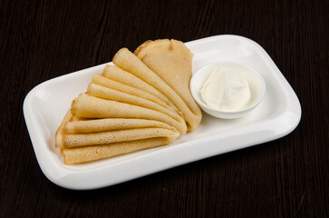 pancakes with sour cream in a white dish