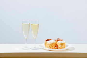 2 Gläser mit Champagne und ein Teller mit süßes Gebäck. 