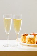 2 Gläser mit Champagne und ein Teller mit süßes Gebäck. 