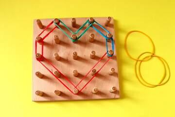 Wooden logic game on a yellow background, top view, selective focus.