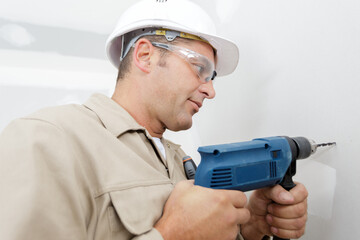 worker drilling a hole into the wall