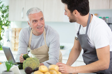Fototapeta premium adult son with his senior fathercooking in the kitchen
