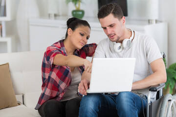 disabled man using laptop sitting next to his girlfriend