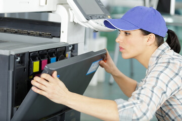 female technician changing ink cartridges of a photocopier