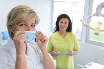 adult dentist puts a protective mask on her mouth