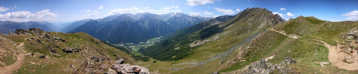 Panoramic view from a hiking trail down to Martell valley and avalanche protection fences on a mountain ridge in the Alps, South Tyrol in Italy