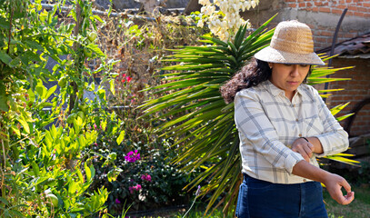 Young woman adjusting the sleeves of her t-shirt, while she is in a garden.