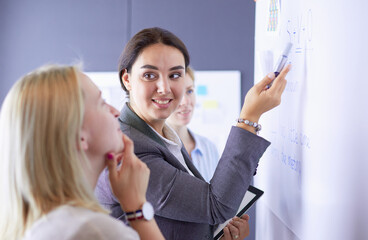 Business, education and office concept - business team with flip board in office discussing something.