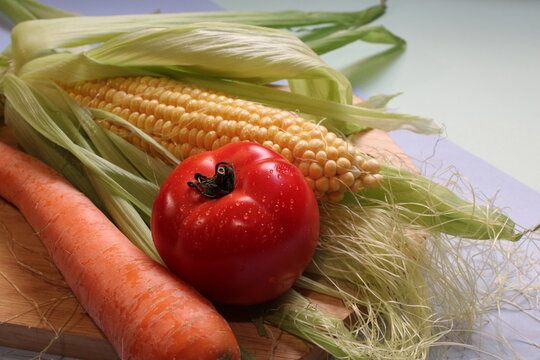 Tabla de cortar con ma&iacute;z, tomate y zanahoria