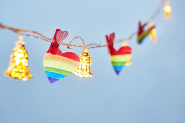 Lgbt valentine's day concept, rainbow heart on garland on blue background, copy space