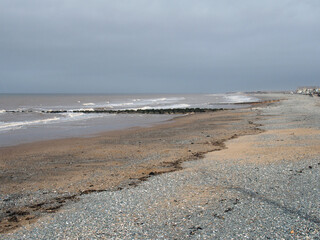 white waves and wooden breakwaters in the sea at thornton cleveleys near blackpool on an overcast cloudy day