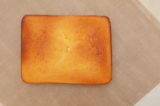 Homemade Sponge Cake, in Portuguese P&atilde;o de L&oacute;. Top of the baked cake dough. Isolated on jute background. Top view. Copy space