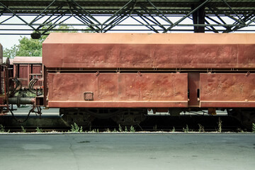 Open hopper car wagon on standby at the platform of a train station in a cargo train shipping...