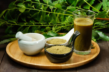 neem powder in black bowl white with white mortar and pestle on wooden background. Neem is an excellent moisturizing and contains various compounds that have insecticidal and medicinal properties. 