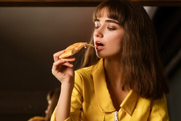 Portrait of a young woman biting a slice of pizza