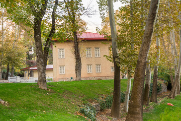 Historic building hidden in the golden forest in autumn with background of mountain in Sa'dabad palace Complex, built by the Qajar and Pahlavi monarchs, located in Shemiran, Greater Tehran, Iran