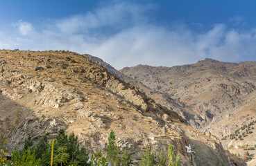 Tochal mountain ridge with rocks and trees in autumn against blue sky, Tehran, Iran. Tochal is a popular recreational region for Tehran's residents