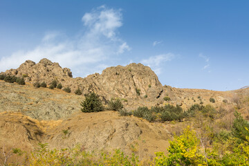 Tochal mountain ridge with rocks and trees in autumn against blue sky, Tehran, Iran. Tochal is a popular recreational region for Tehran's residents