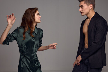 A woman and a man stand opposite on a gray background and gesticulate with their hands