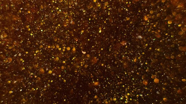 Macro shot of gold glitter. Slow mo. Amazing background. 4K. Gold liquid. Boke.