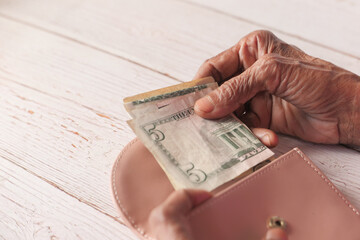 Close up of senior women hand saving cash in wallet 