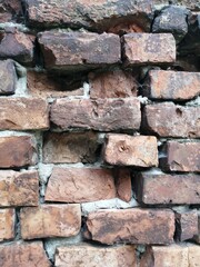 industrial background and texture of dark ancient brick wall with visible recessed broken bricks