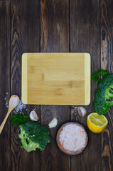 Broccoli, garlic, lemon slice and pink himalayan salt. Food background with copy space for text, empty wooden cutting board with ingredients for cooking