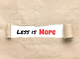 Phrase LESS IS MORE appearing behind torn brown paper.For background purpose.