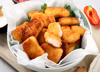 Fried crispy chicken nuggets with ketchup on wooden board