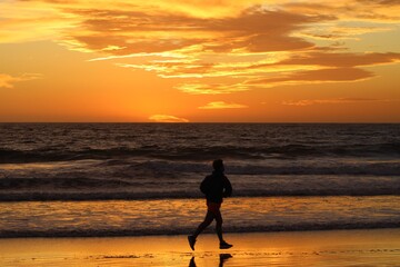 Man jogging by the water during a beach sunset 