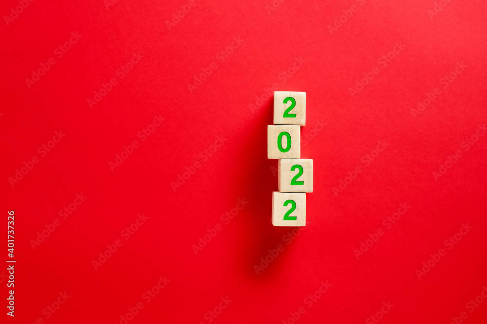 Wall mural Wooden blocks with the Christmas new year eve 2022 written against red background.