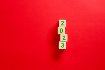 Wooden blocks with the Christmas new year eve 2023 written against red background.