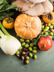 Green background with raw organic vegetable, fruit. Autumn, winter veggies concept, healthy food. Top view