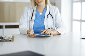 Unknown woman-doctor standing in clinic and using tablet pc, close-up. Data and best service in medicine and healthcare