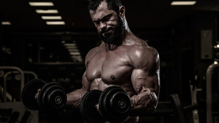 Fototapeta na wymiar strong young bearded caucasian man lifting dumbbells in night sport gym