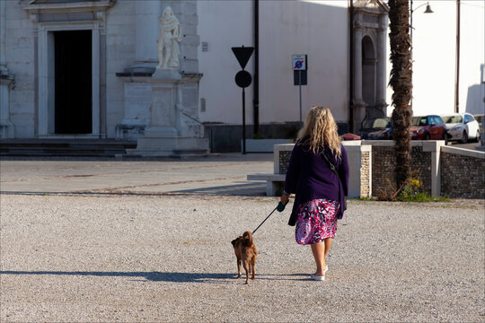 Donna che porta a passeggio il cane in centro storico della citt&agrave;.