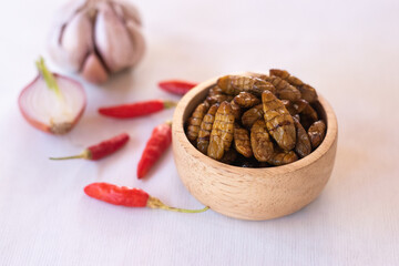 
silkworm pupa in wooden bow as edible insects on white background, high protein insect