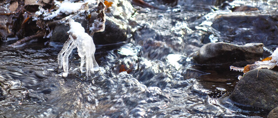 Partially frozen and snow covered creek in beautiful prír with icicles