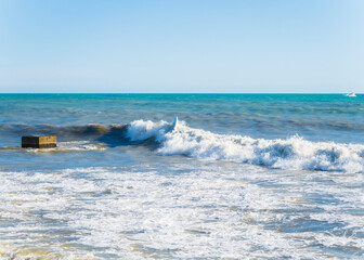 A man in a black wetsuit on the surf of the Black Sea Sochi 05.12.2019