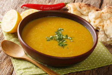 Red lentil puree soup served with breads and lemon close-up in a bowl on the table. horizontal