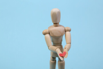 Wooden puppet with a heart on a blue background.