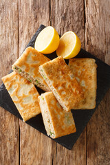 Murtabak is a stuffed pancake or pan-fried bread with meat, egg and green onion closeup in the board on the table. vertical top view above