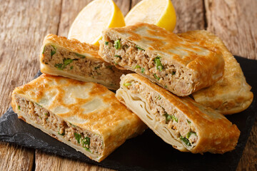 Tasty Mutabbaq Middle Eastern folded pan-fried flatbreads, stuffed with lightly spiced mince meat and egg. closeup in the board on the table. horizontal