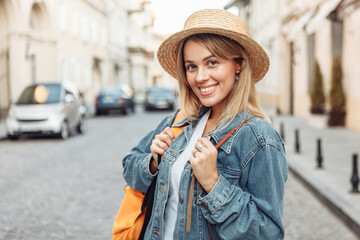 Nice beautiful millennial tourist woman with backpack in jeans jacket  discover European city at holiday travel.