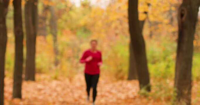 Girl doing cardio in the autumn forest of a city park. Attractive woman athlete wearing stylish sport clothing and grey sneakers.
