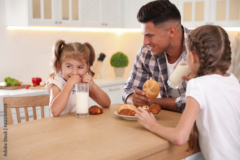 Wall mural Little girls and their father eating together at table in modern kitchen