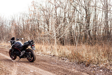 Fototapeta na wymiar Black stylish sport motorcycle in autumn forest.
