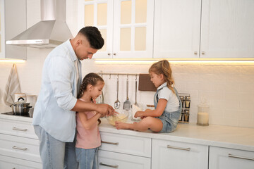 Little girls and their father cooking together in modern kitchen