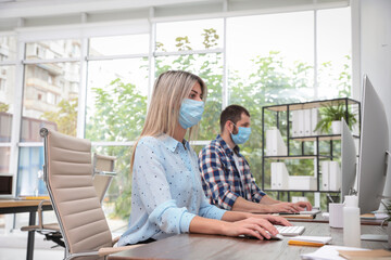 Office employees in respiratory masks at workplace